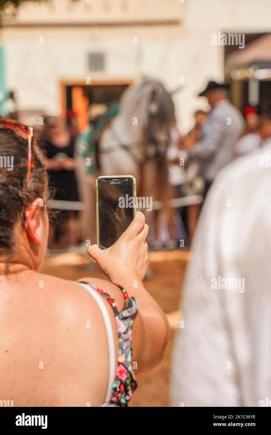 Donna in possesso di una registrazione video telefonica durante un evento a cavallo, Andalusia, Costa del Sol, Spagna Foto Stock