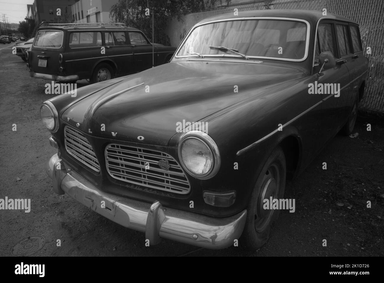 Una foto in scala di grigi di una vecchia auto Volvo parcheggiata in un parcheggio abbandonato Foto Stock