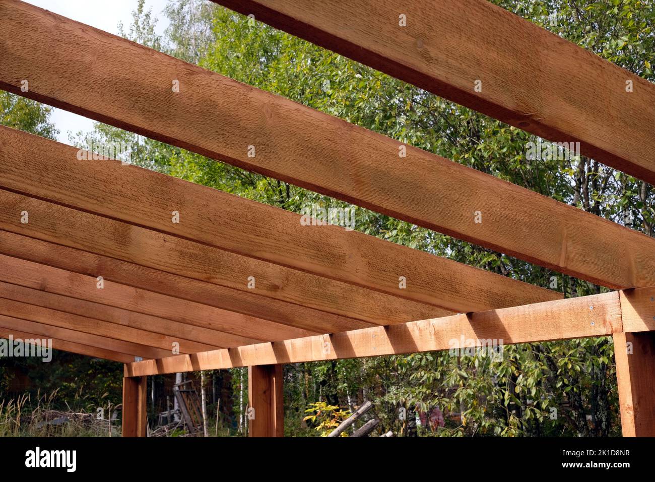 Il processo di costruzione di un baldacchino di legno dalle tavole marroni nella campagna in giorno di estate Foto Stock