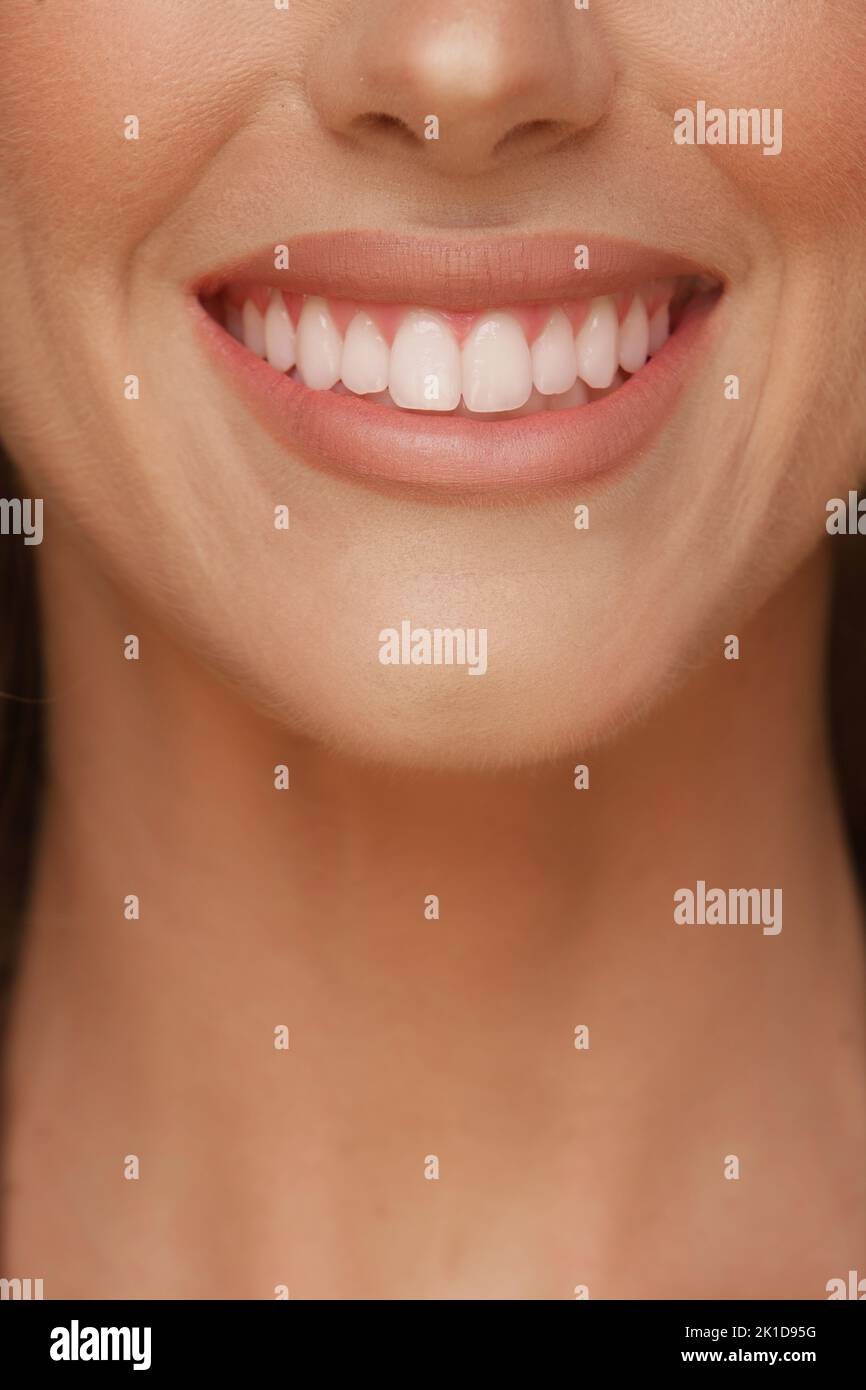 particolare del sorriso di una donna con denti bianchi perfetti e labbra con rossetto Foto Stock