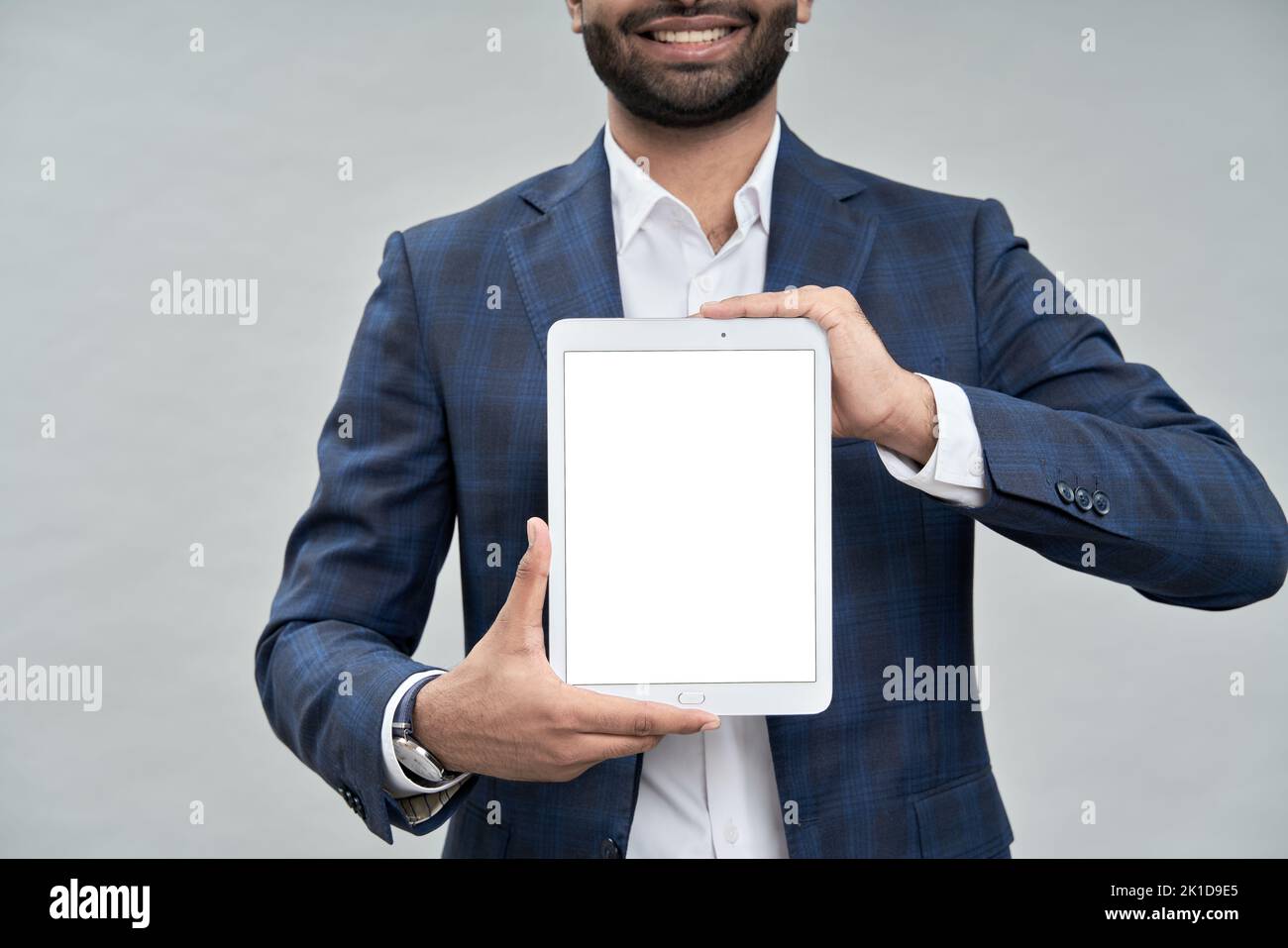 Un uomo d'affari sorridente che indossa una tuta che mostra il mockup del tablet digitale. Foto Stock