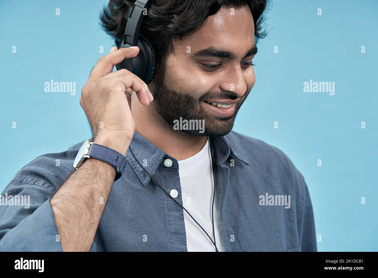 Sorridente studente arabo che indossa cuffie per ascoltare musica. Primo piano Foto Stock