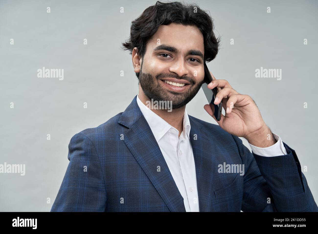Sorridente giovane uomo d'affari arabo indiano che parla al telefono facendo una chiamata. Foto Stock