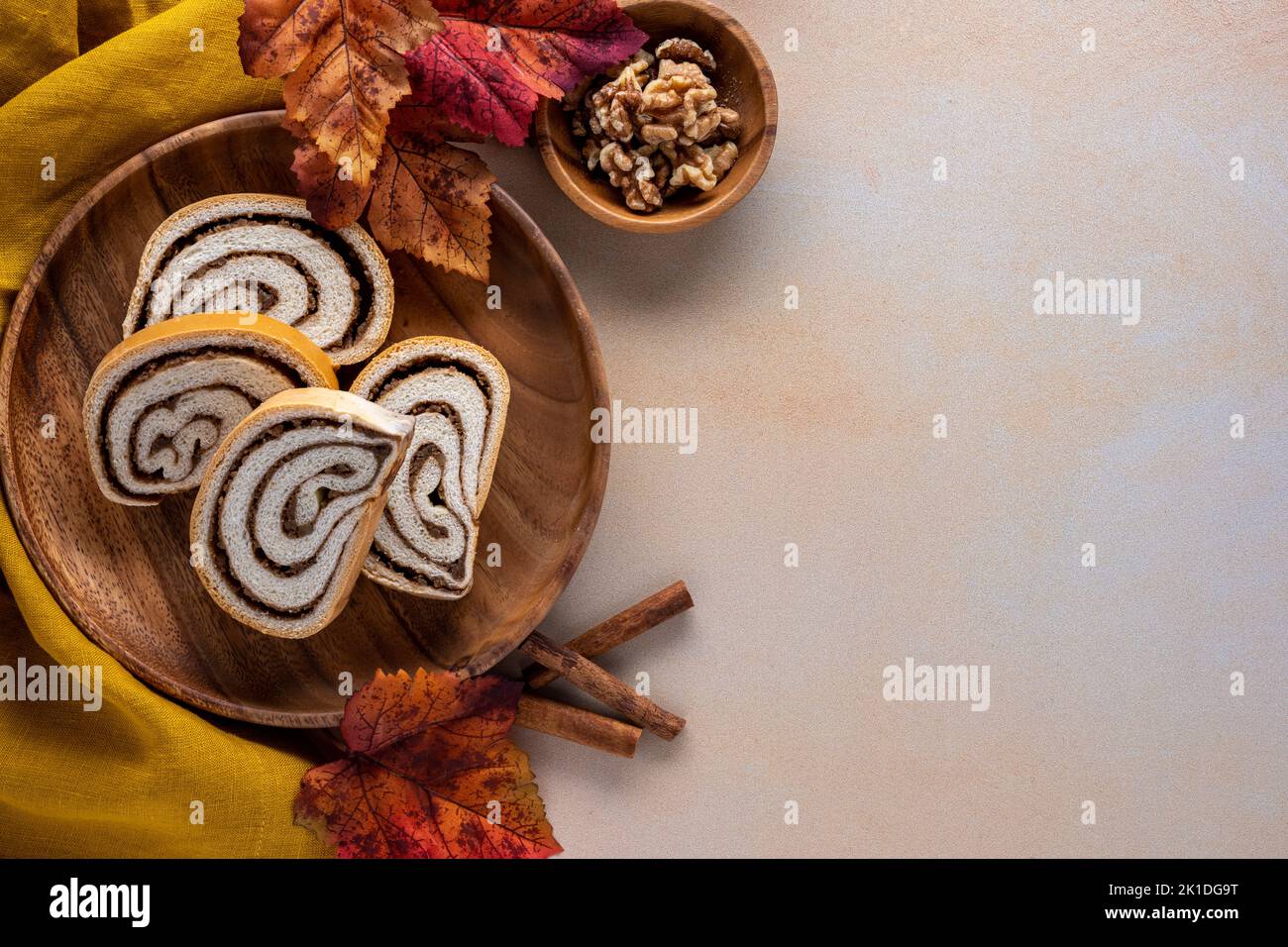 Thanksgiving o sfondo dessert autunnale con rotolo di noci affettate su un piatto di legno con foglie di caduta e noci Foto Stock