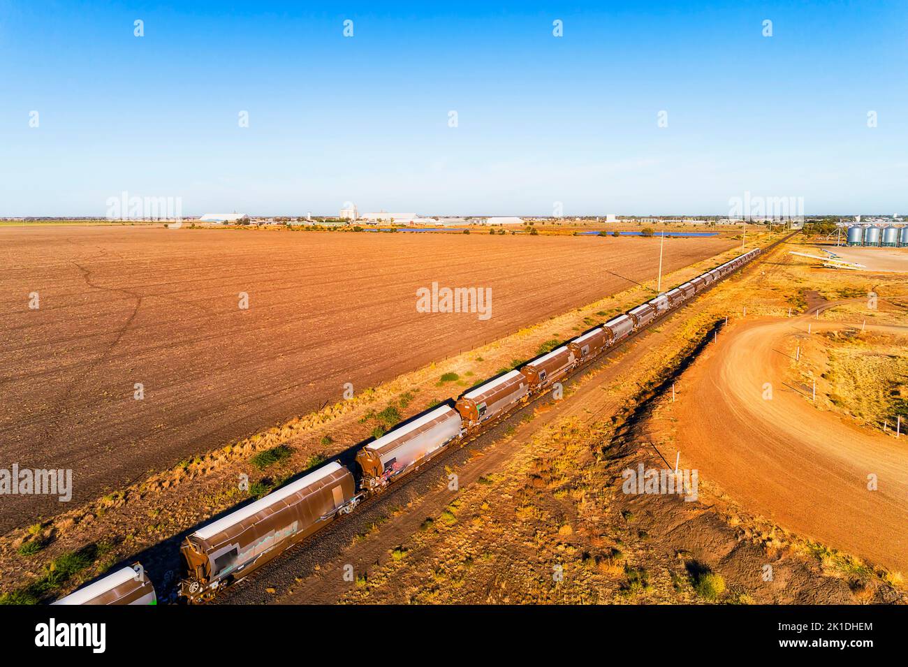 Treno merci a grano lungo presso il sito di deposito di ascensore silo nella città di Moree del bacino artesiano australiano. Foto Stock