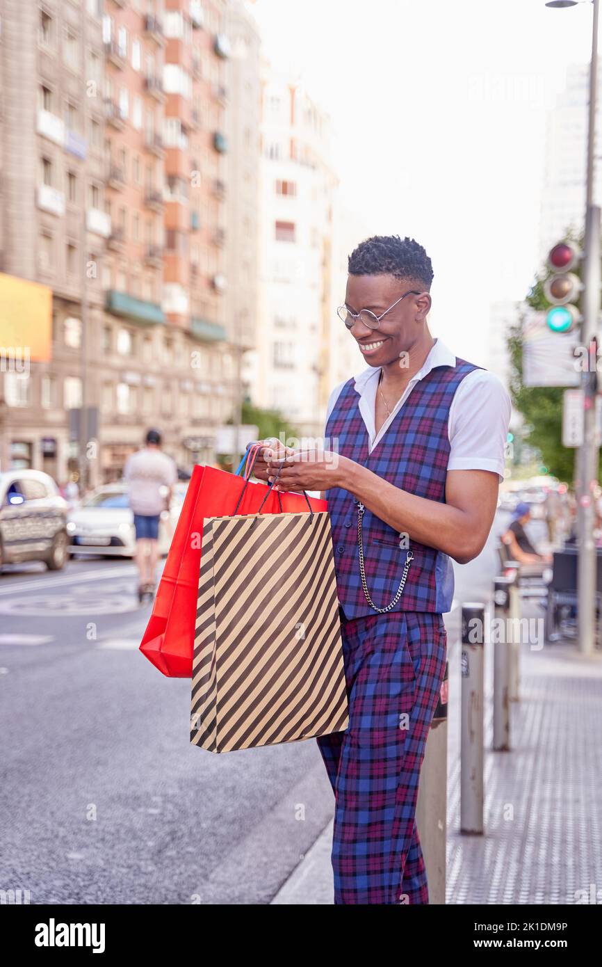 Giovane afro-americano che guarda all'interno della shopping bag all'aperto Foto Stock