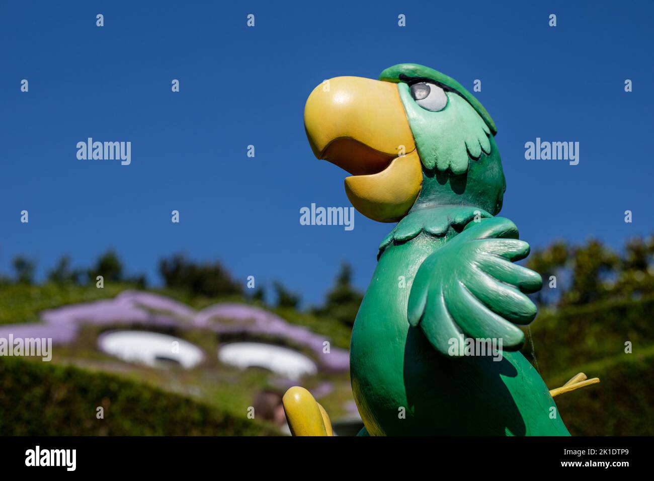Un primo piano di una statuina verde di pappagallo contro un cielo blu a Disneyland a Parigi Foto Stock