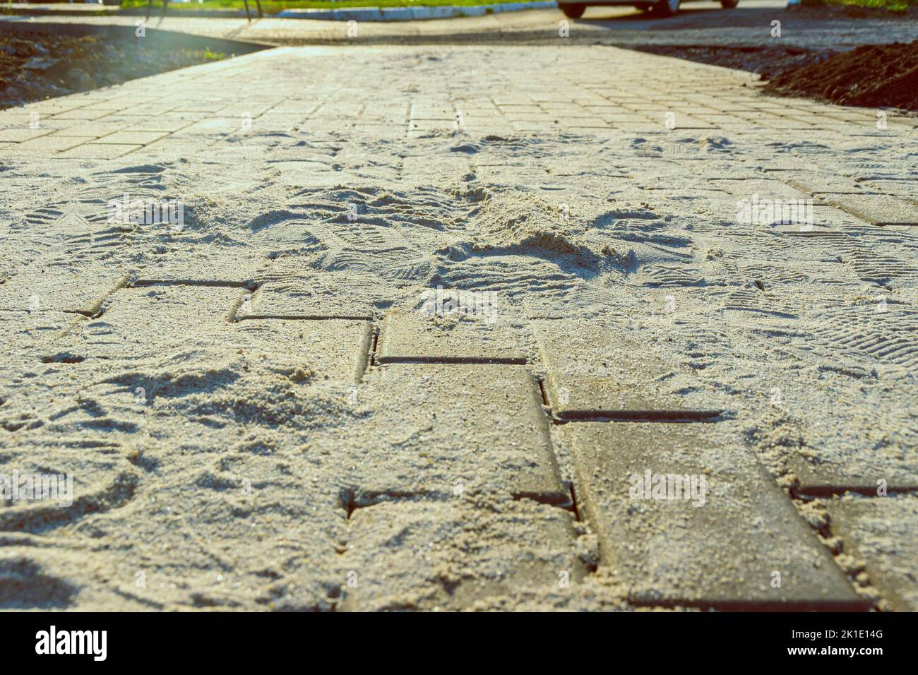 lastre di pavimentazione in pietra artificiale in fase di riempimento dei giunti con sabbia setacciata asciutta, fuoco selettivo Foto Stock