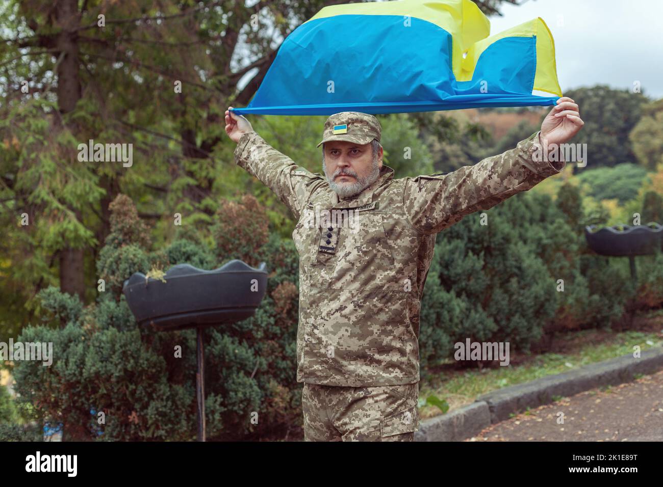 L'uomo militare ucraino tiene la bandiera dell'Ucraina nelle sue mani. Guerra, conflitto, Ucraina. Foto Stock