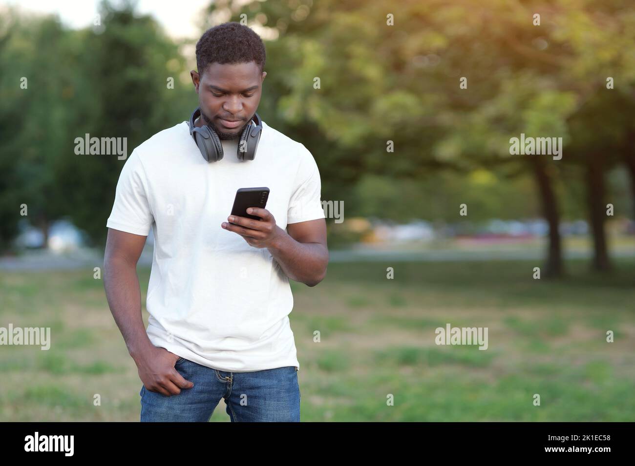 Un ragazzo afro-americano guarda lo smartphone e legge le notizie Foto Stock