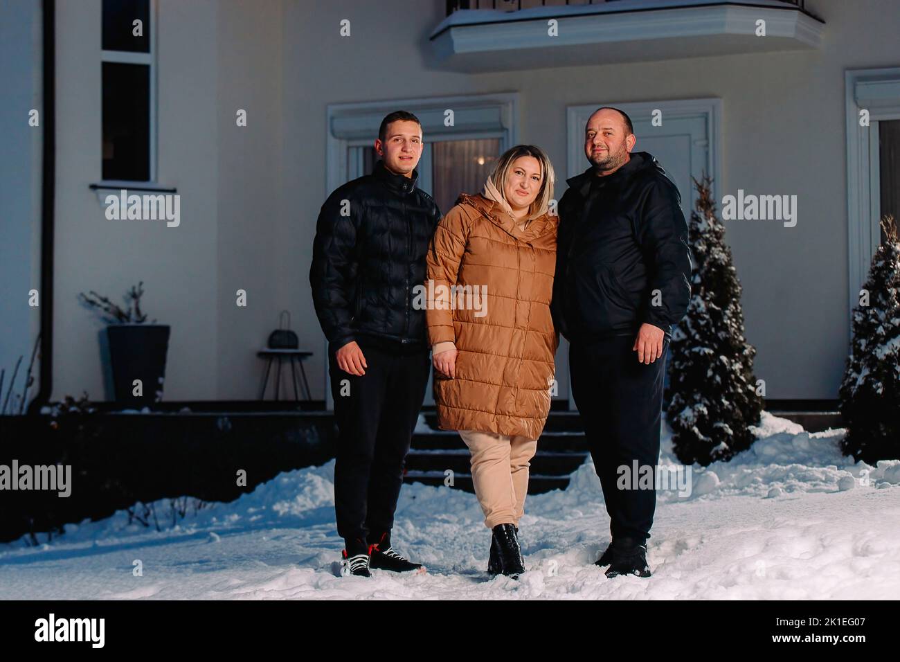 Foto a tutta lunghezza di una bella famiglia di una donna e due uomini in piedi fuori sulla neve in vacanza di nuovo anno. Foto Stock