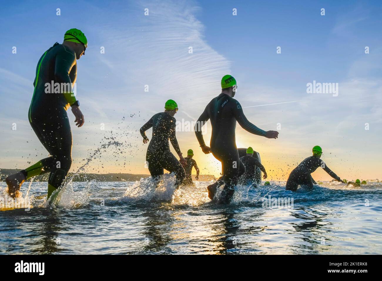 Weymouth, Dorset, Regno Unito. 18th settembre 2022. Meteo nel Regno Unito. Gli atleti che gareggiano nel triathlon Ironman 70,3 di Weymouth sono contornati contro l'alba mentre entrano in mare per la loro nuotata all'inizio dell'evento in una fredda e soleggiata mattina autunnale. Picture Credit: Graham Hunt/Alamy Live News Foto Stock