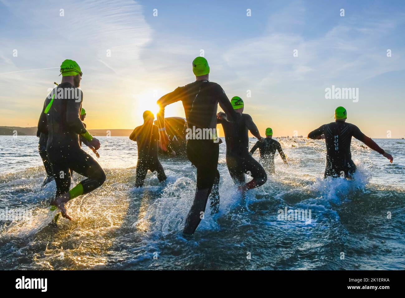 Weymouth, Dorset, Regno Unito. 18th settembre 2022. Meteo nel Regno Unito. Gli atleti che gareggiano nel triathlon Ironman 70,3 di Weymouth sono contornati contro l'alba mentre entrano in mare per la loro nuotata all'inizio dell'evento in una fredda e soleggiata mattina autunnale. Picture Credit: Graham Hunt/Alamy Live News Foto Stock