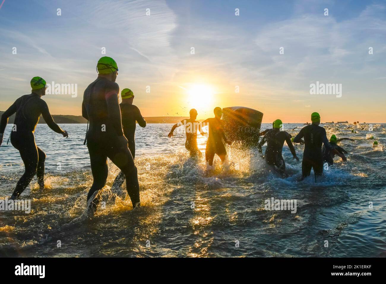 Weymouth, Dorset, Regno Unito. 18th settembre 2022. Meteo nel Regno Unito. Gli atleti che gareggiano nel triathlon Ironman 70,3 di Weymouth sono contornati contro l'alba mentre entrano in mare per la loro nuotata all'inizio dell'evento in una fredda e soleggiata mattina autunnale. Picture Credit: Graham Hunt/Alamy Live News Foto Stock