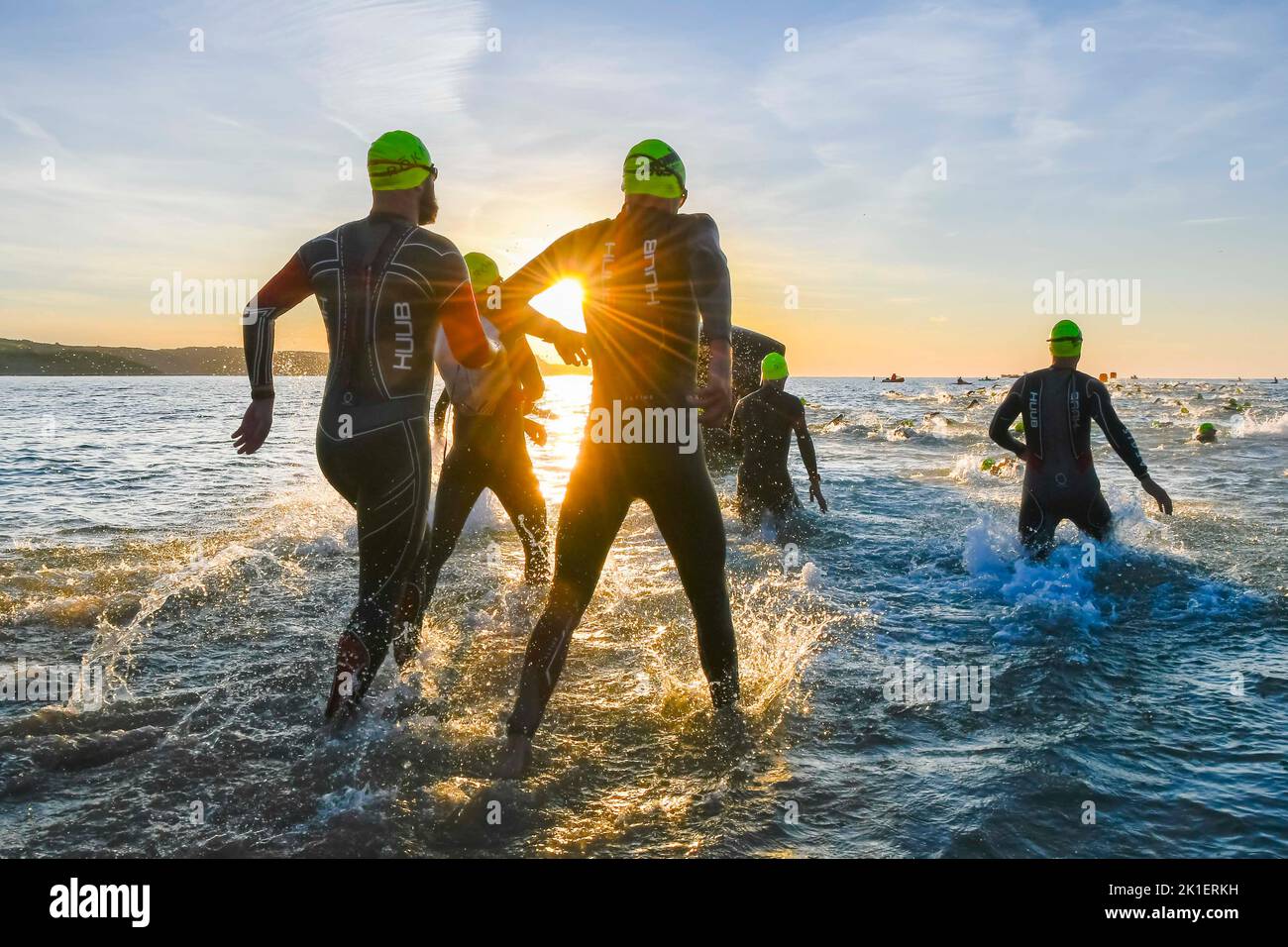 Weymouth, Dorset, Regno Unito. 18th settembre 2022. Meteo nel Regno Unito. Gli atleti che gareggiano nel triathlon Ironman 70,3 di Weymouth sono contornati contro l'alba mentre entrano in mare per la loro nuotata all'inizio dell'evento in una fredda e soleggiata mattina autunnale. Picture Credit: Graham Hunt/Alamy Live News Foto Stock