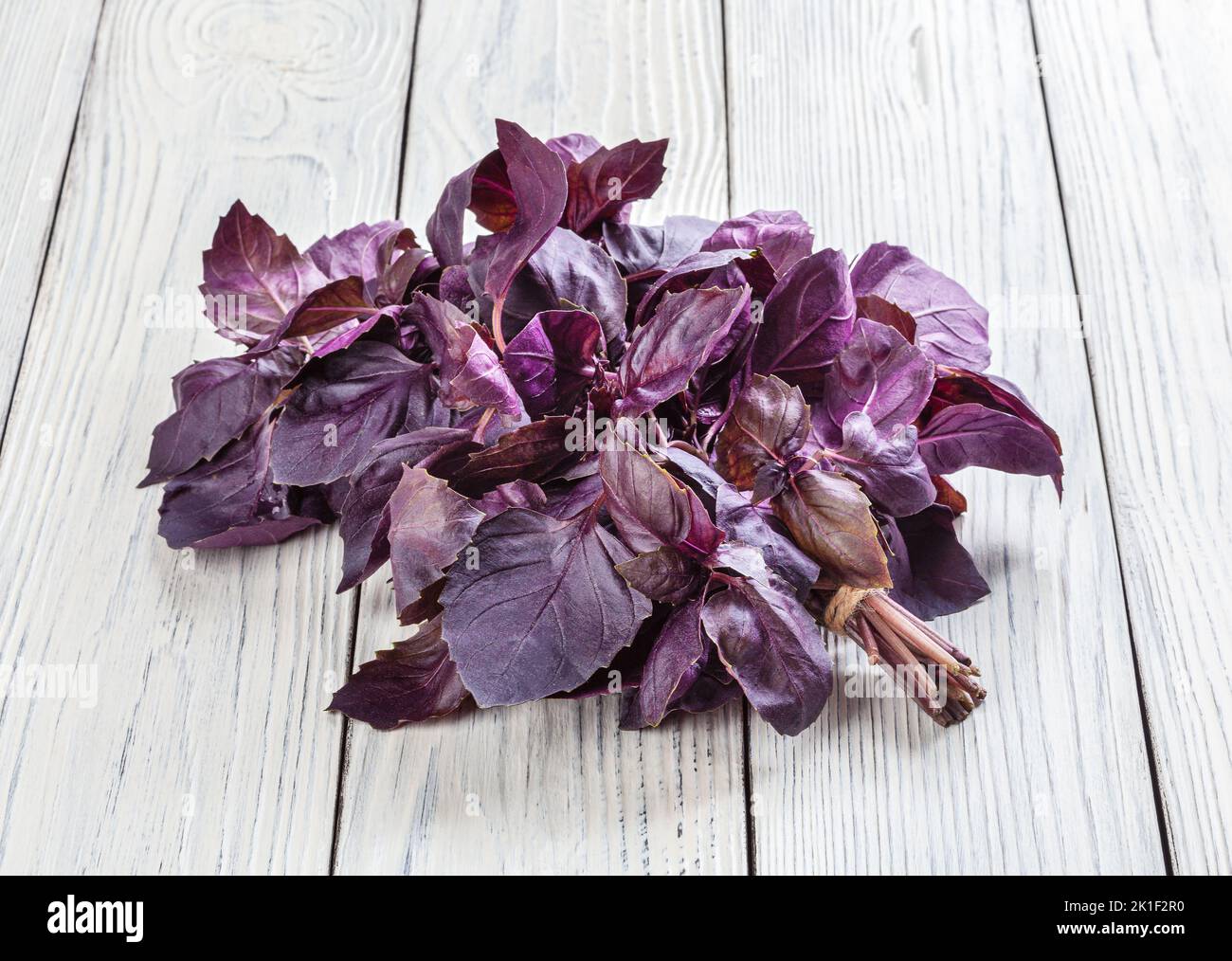Foglie di basilico viola fresco su sfondo bianco di legno Foto Stock
