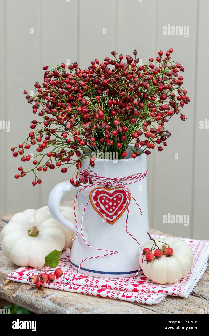 bouquet di fianchi di rosa in tazza di birra come decorazione autunnale Foto Stock