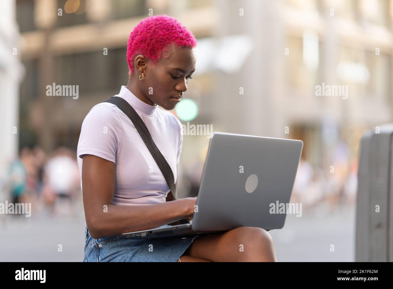 Giovane donna africana che lavora con il portatile per strada Foto Stock