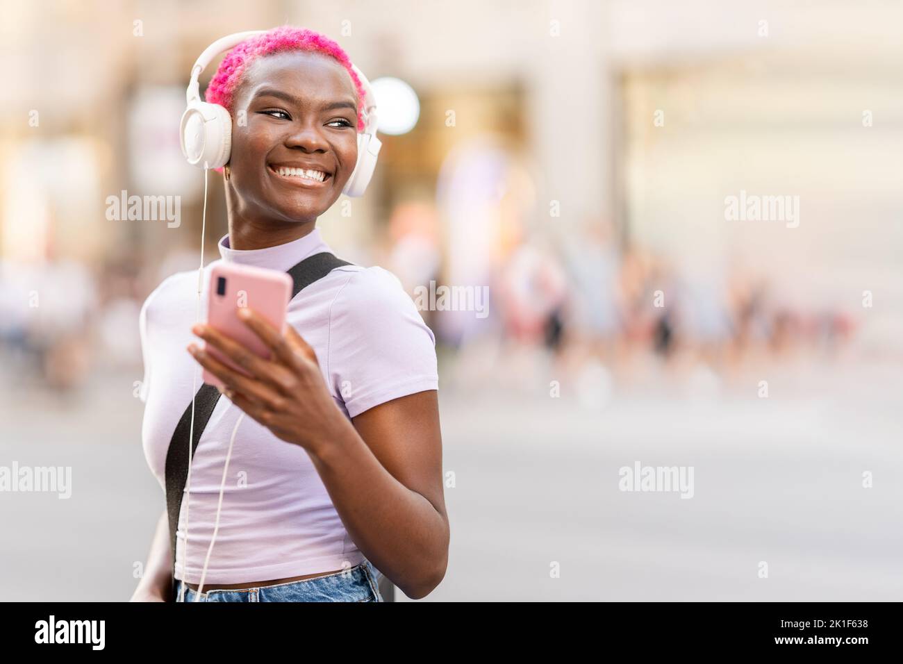 Donna africana sorridente sorridente mentre ascolta musica all'aperto Foto Stock