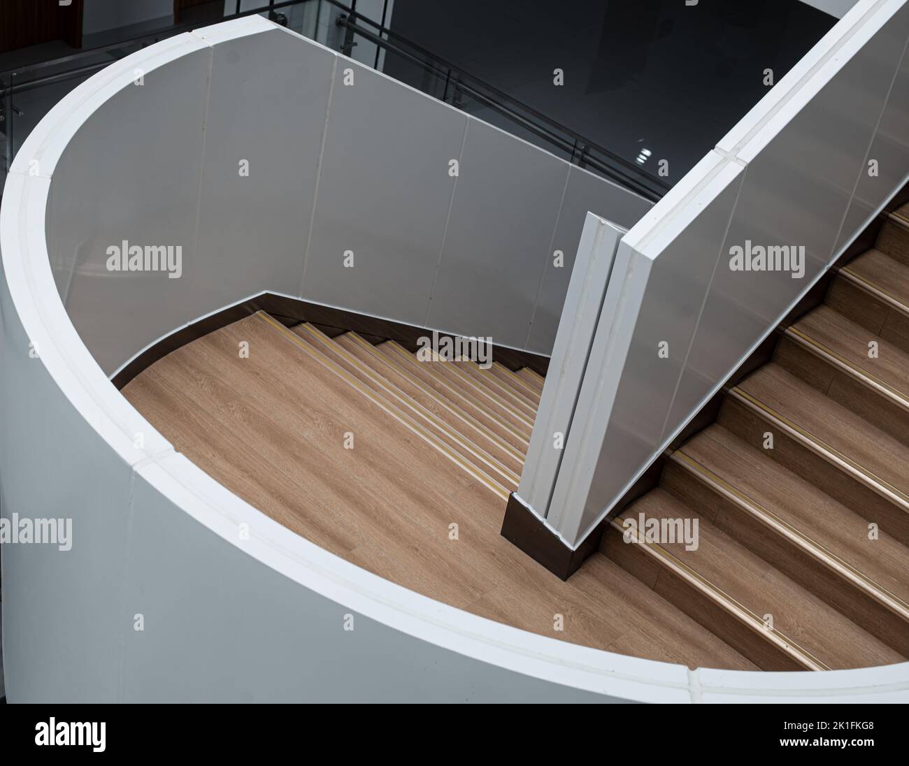 Un alto angolo di una moderna scala marrone con ringhiere bianche Foto Stock