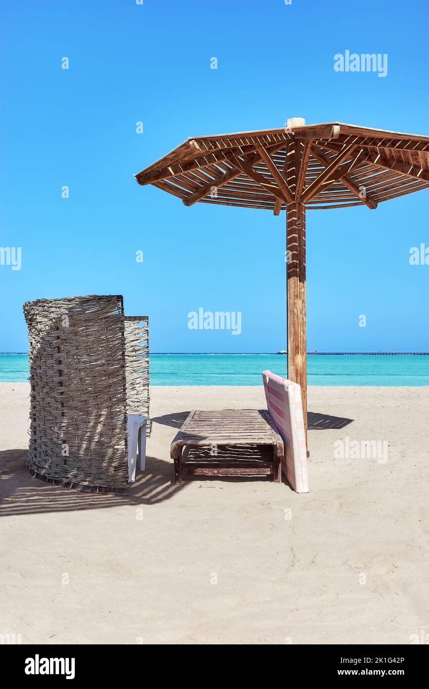 Ombrellone in legno, lettino e parabrezza sulla spiaggia, Marsa Alam, Egitto. Foto Stock