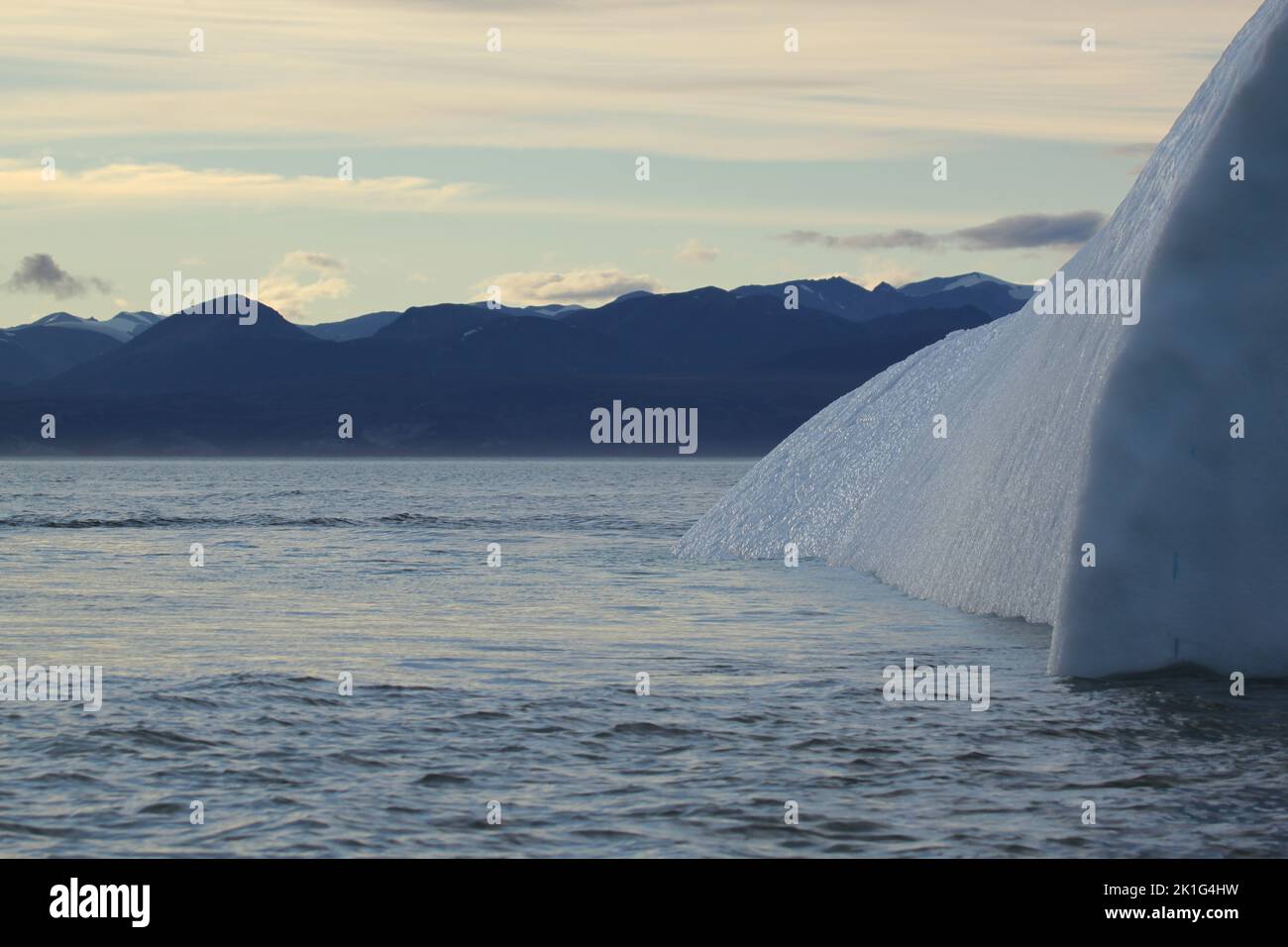 Vista laterale di un iceberg e ghiaccio arenato la sera in un paesaggio artico, vicino a Pond Inlet, Nunavut, Canada Foto Stock