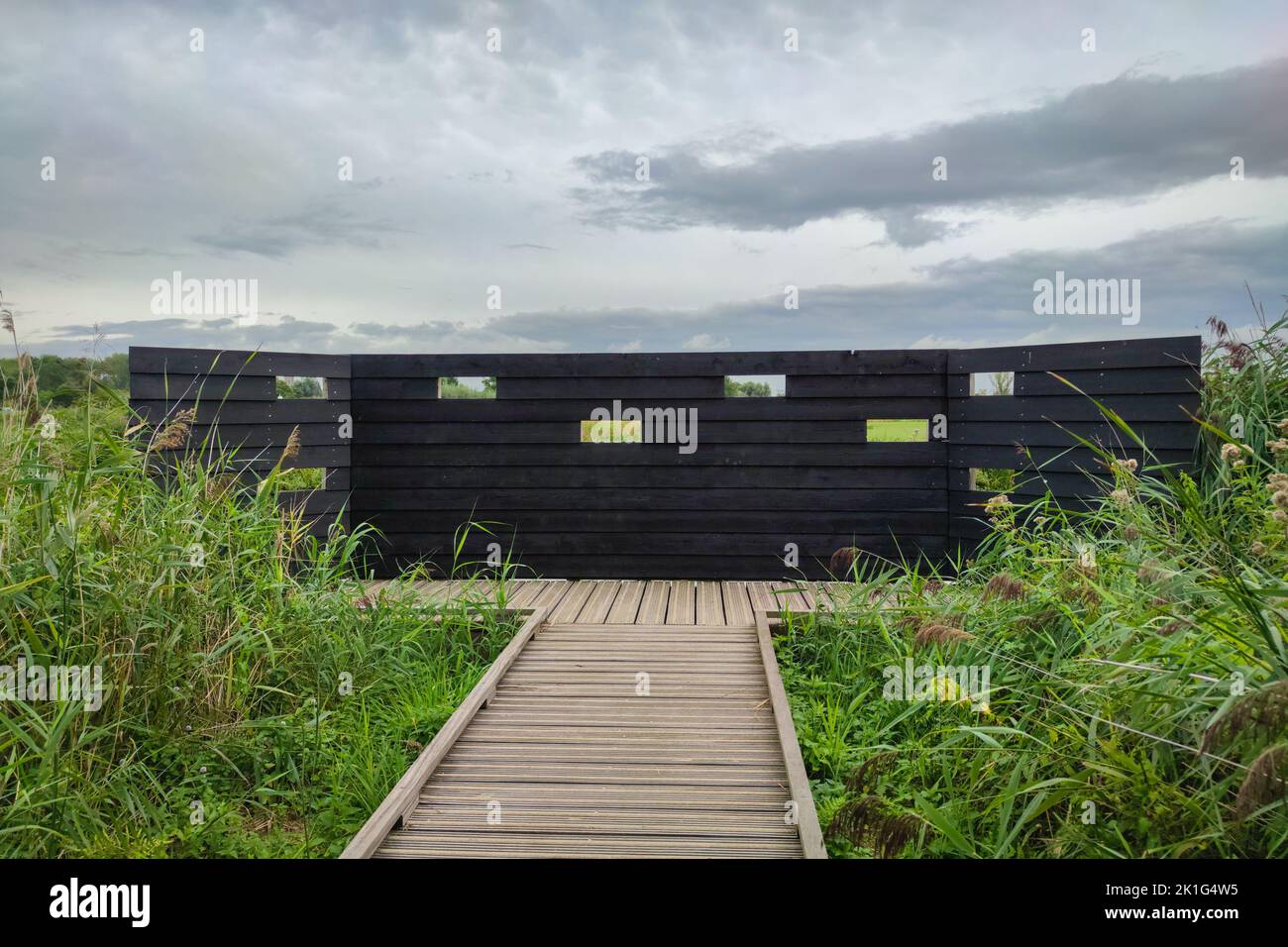 Barriera di legno con fori che serve come un luogo di bird watching nella zona naturale 't Weegje vicino Gouda, Paesi Bassi Foto Stock