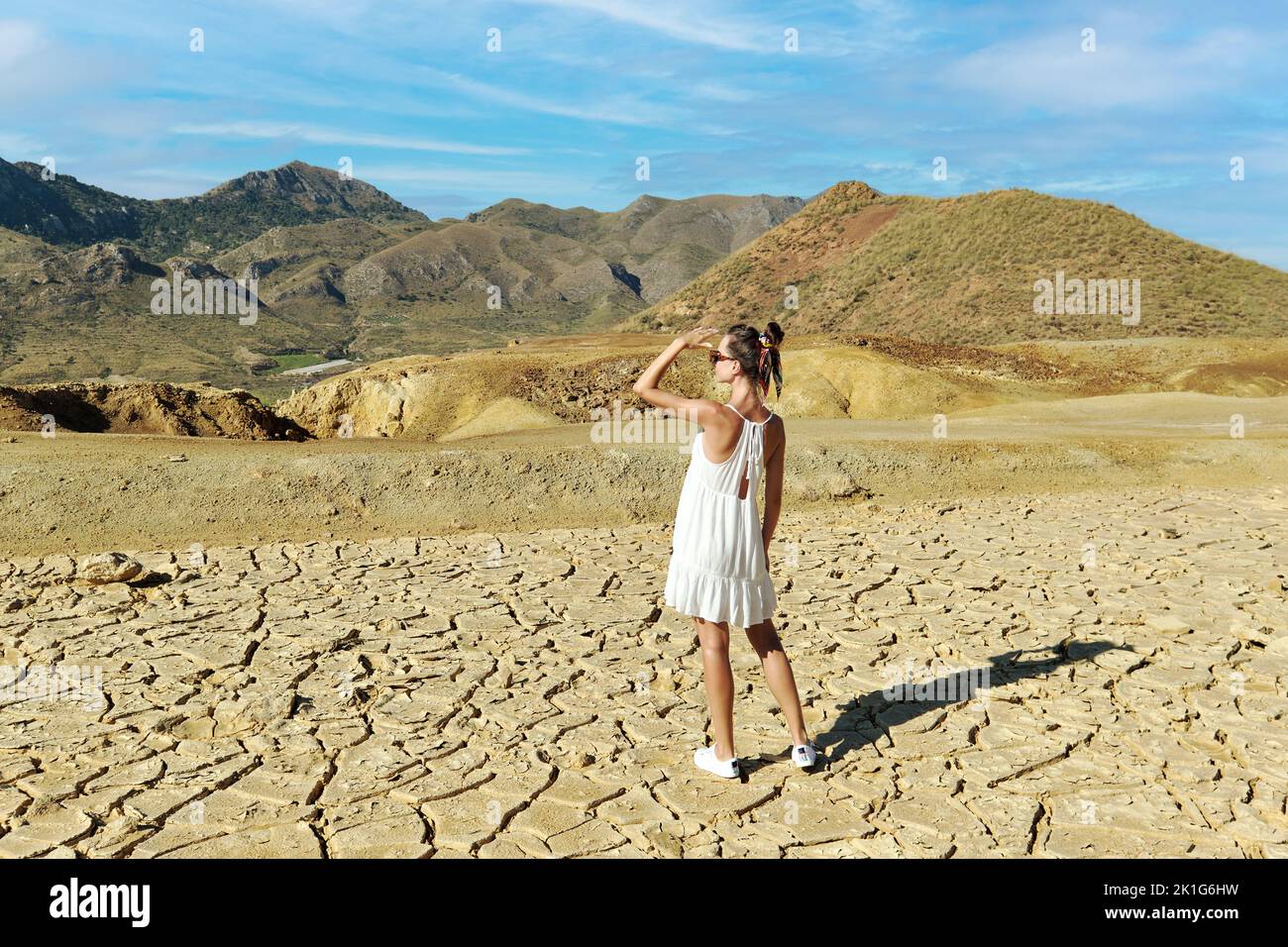 Vista posteriore giovane turista femminile in vestito bianco Visita vecchie miniere abbandonate di Mazarron a Murcia su sfondo cielo blu durante la giornata di sole estate. Corsa d Foto Stock