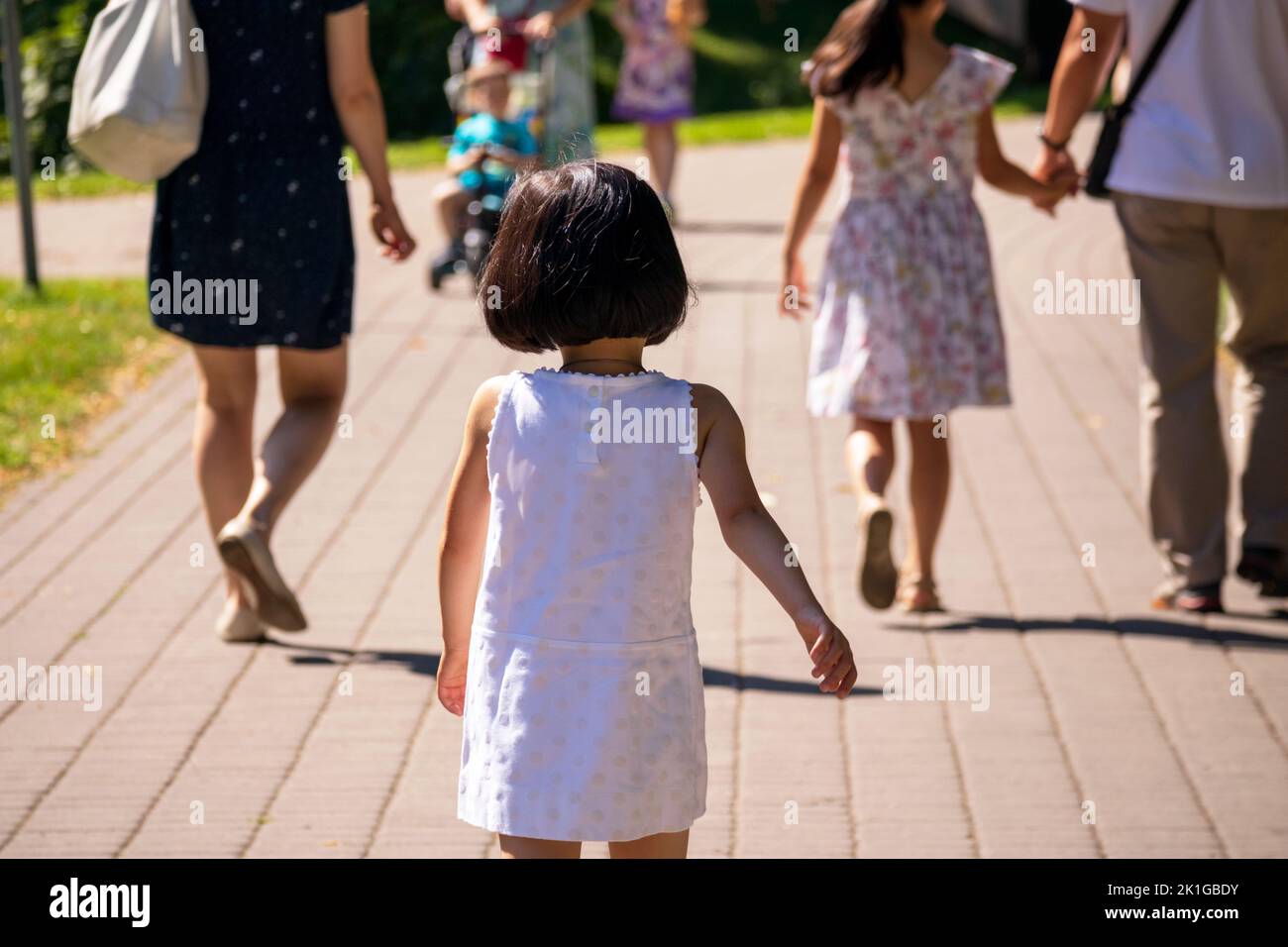 Una giovane ragazza in un vestito bianco e nero cammina per la strada Foto Stock