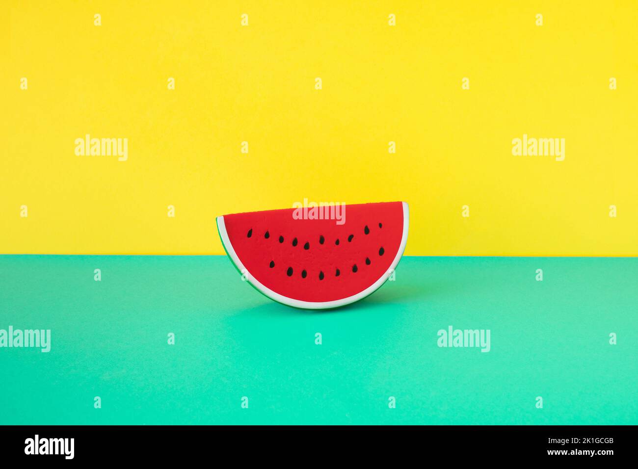 Fettina di cocomero in gomma su fondo turchese e giallo. Concetto estivo minimal. Foto Stock