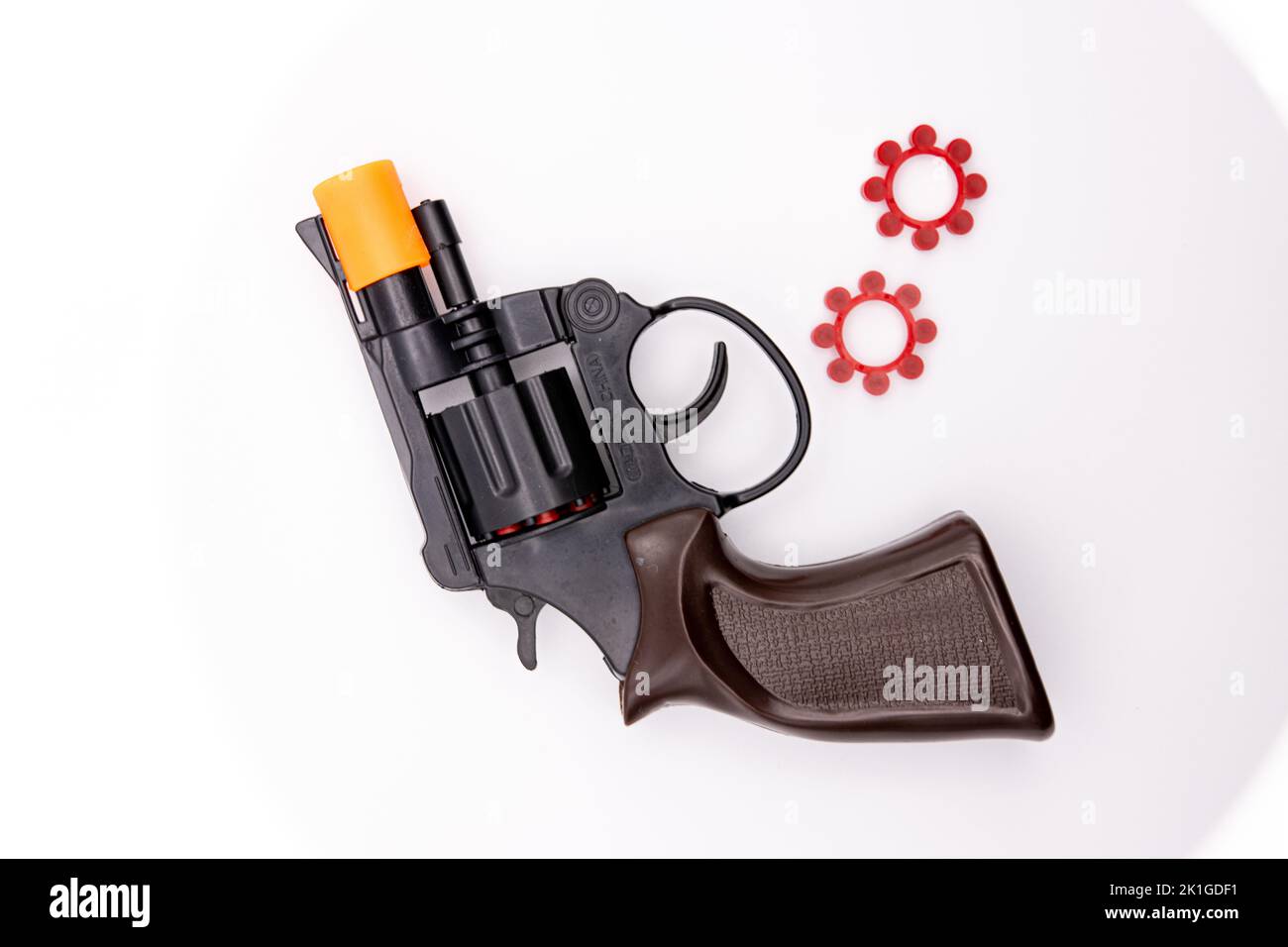 Un primo piano di una pistola giocattolo revolver con le sue munizioni su uno sfondo bianco Foto Stock