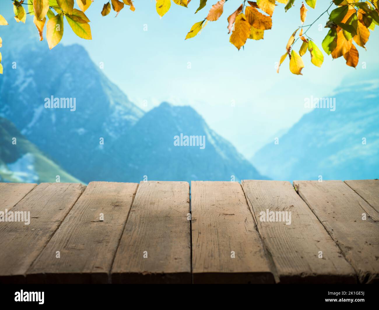 Autunno sfondo. Giornata di sole con vista sulle montagne e terrazza in legno. Tavolo di legno vuoto in natura Foto Stock