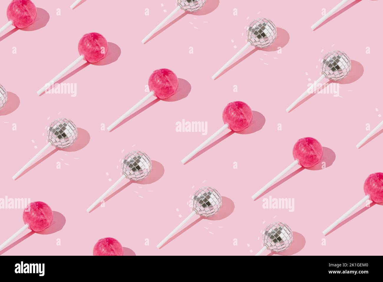 Lollipop caramella e disco palla su lollipop stick pattern su sfondo rosa. Vista dall'alto. Concetto minimo. Foto Stock