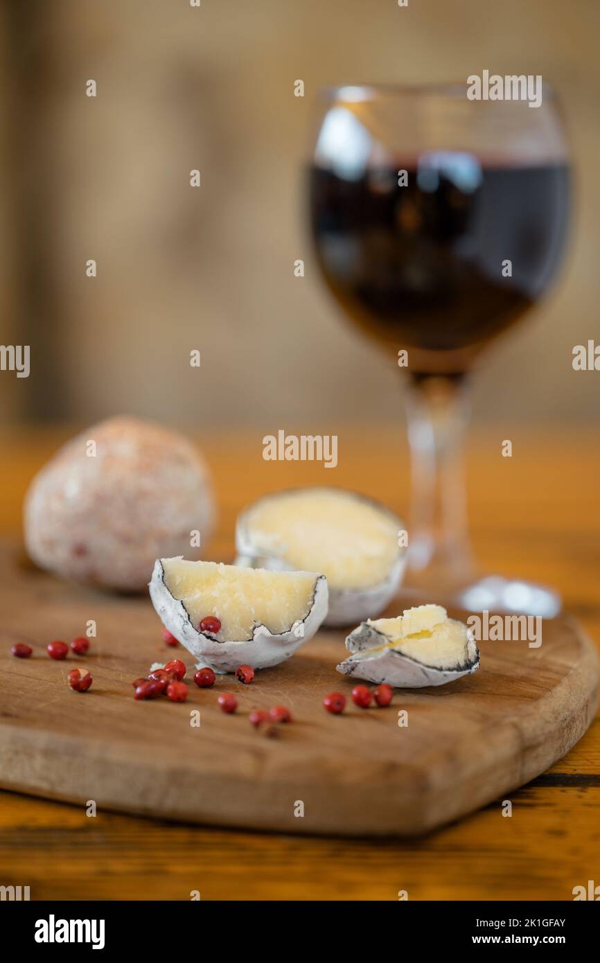 Palline di Belper knole con aglio e pepe rosa in cenere di legno. Un bicchiere di vino rosso. Formaggio svizzero. Formaggio lattico fermentato. SDOF Foto Stock