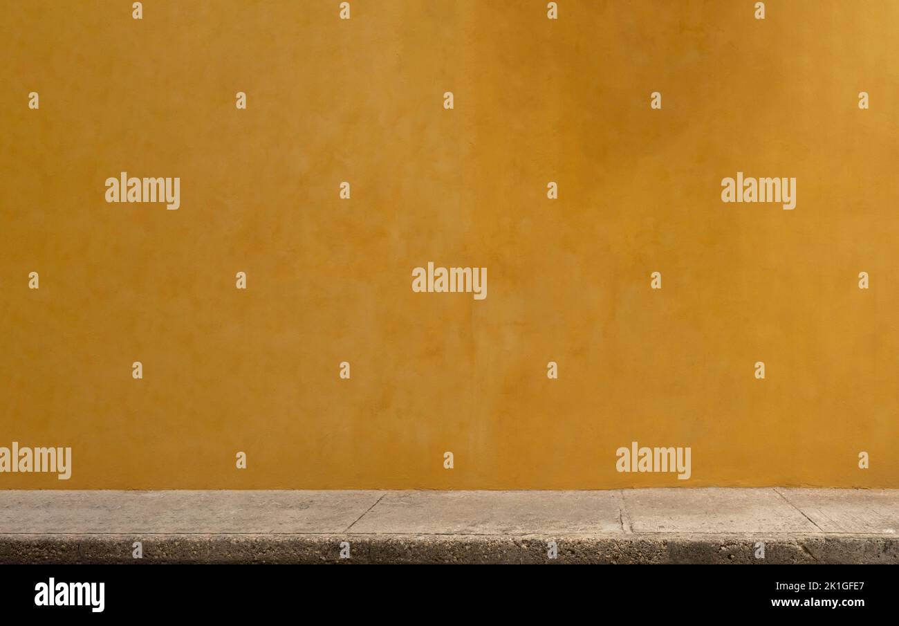 Parete gialla colorata della casa caraibica con struttura in stucco per lo sfondo. Spazio esterno minimo. Foto Stock