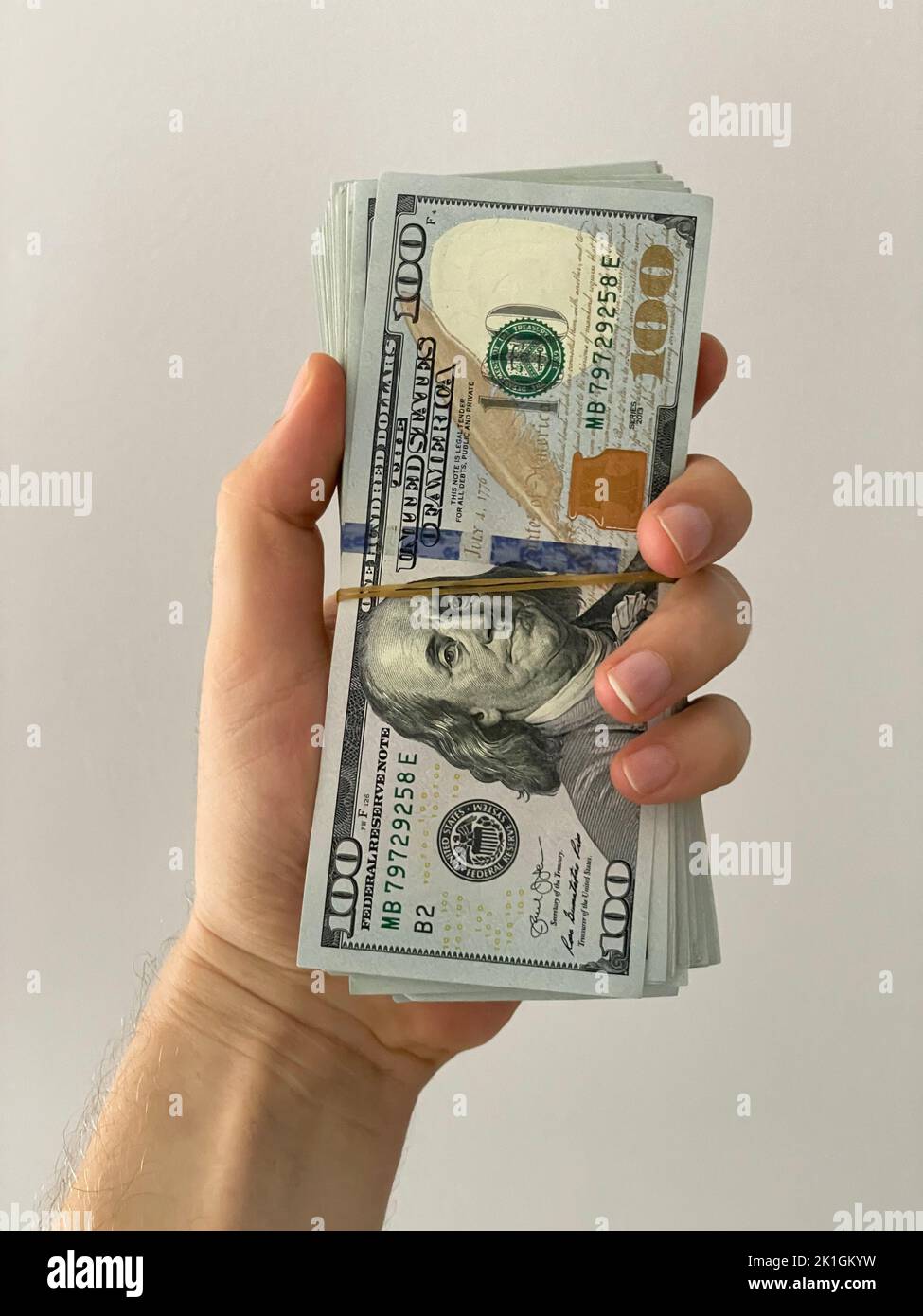 Un uomo che tiene una bacchetta di denaro. Dollari in una mano Foto Stock