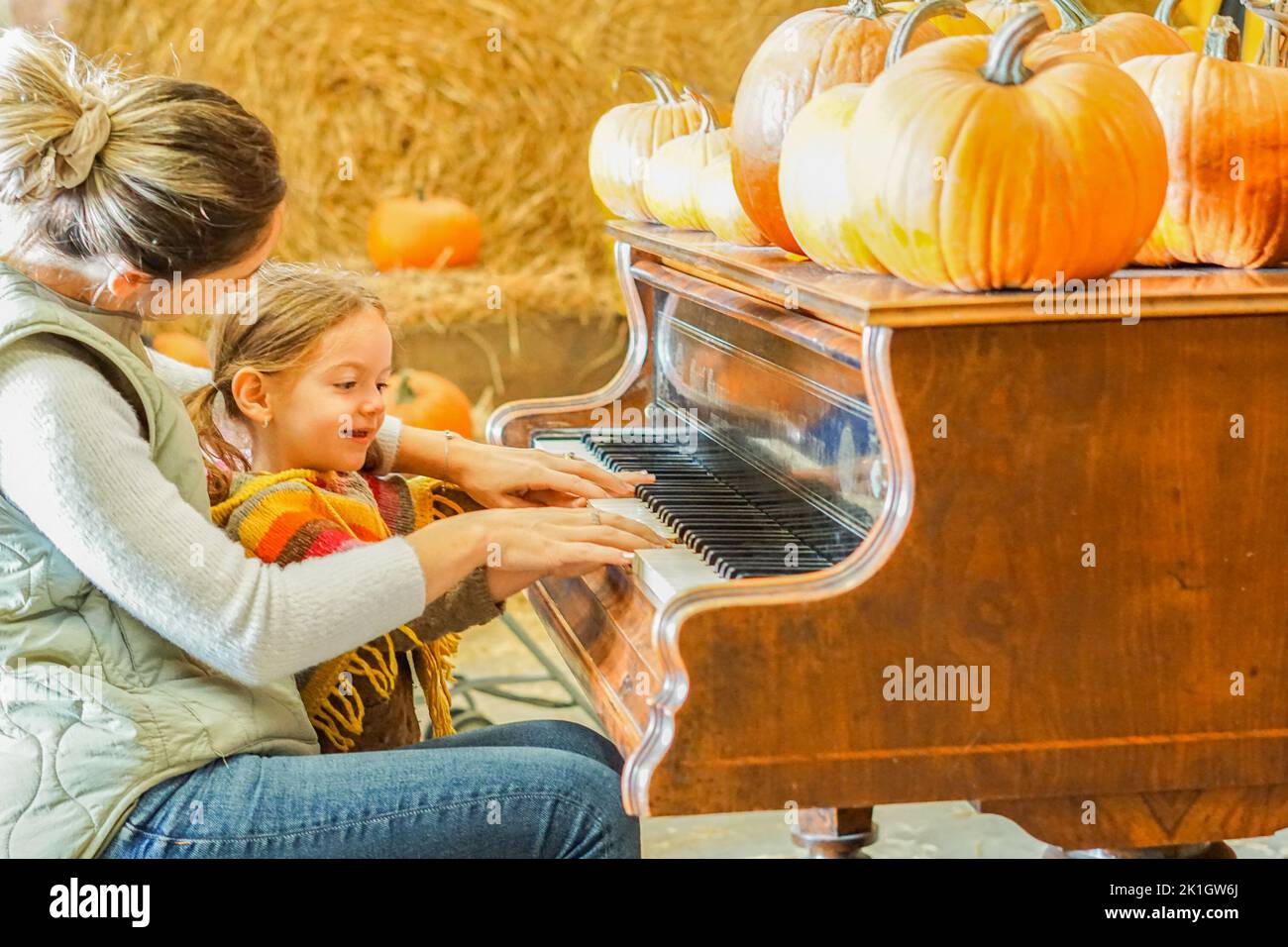 Madre che insegna a sua figlia come suonare il pianoforte nella stagione di Halloween - mamma e bambina che si godono la zucca patch Foto Stock