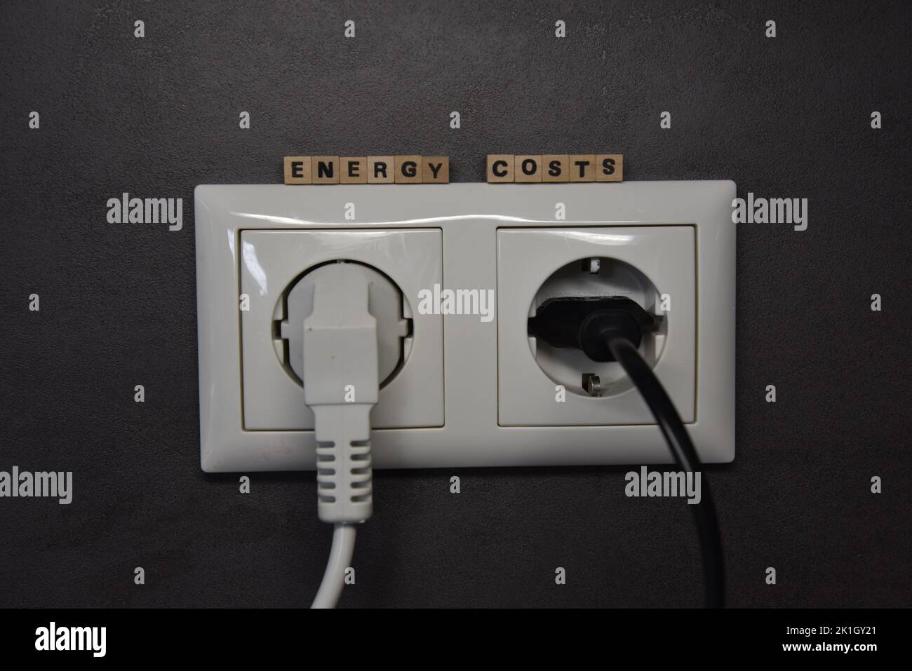 la parola per i costi di energia con mattoni wodden e una presa Foto Stock