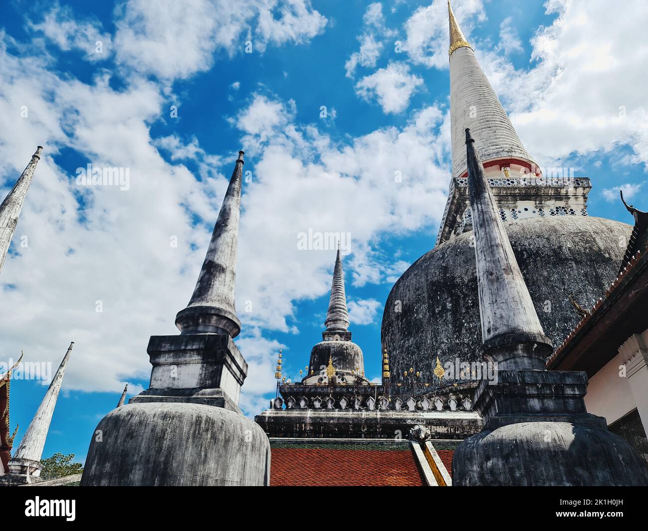 Un tiro a basso angolo del tempio Wat Phra Mahathat Woramahawihan in Thailandia contro un cielo blu nuvoloso Foto Stock