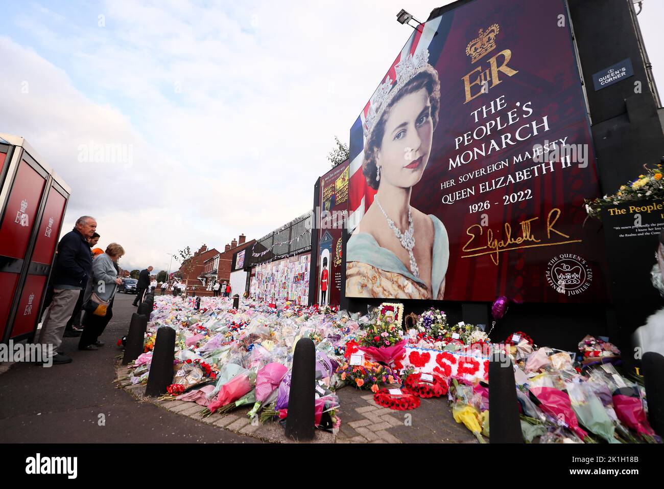Dopo la scomparsa del Monarca britannico, la gente depone fiori in un murale raffigurante la Regina Elisabetta II sulla Shankill Road a Belfast. Foto Stock