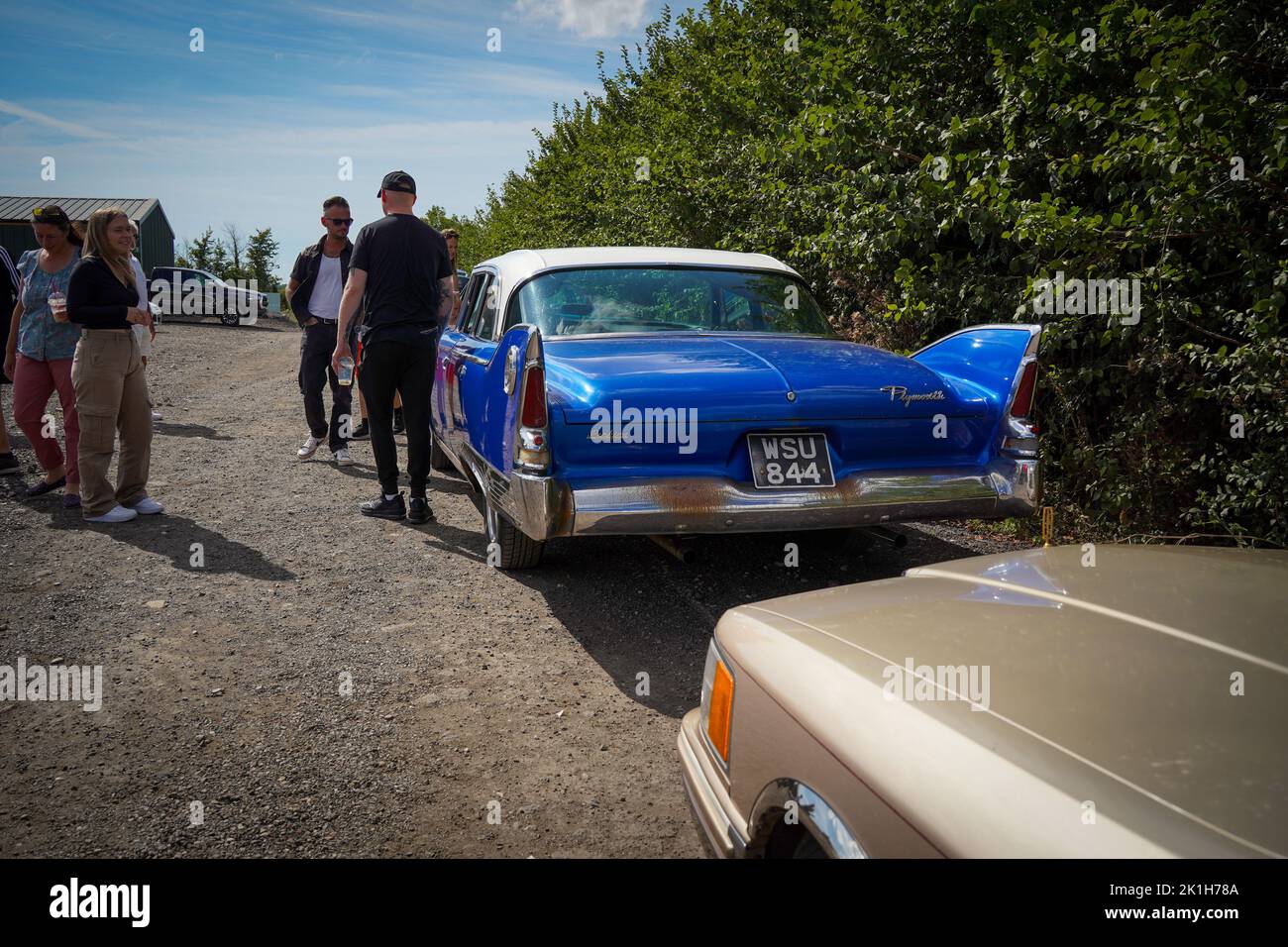 Exeter, Regno Unito-Agosto 2022: Persone che visitano una mostra di auto classica alla Greendale Farm vicino Exeter con un Plymouth 1960 in primo piano Foto Stock