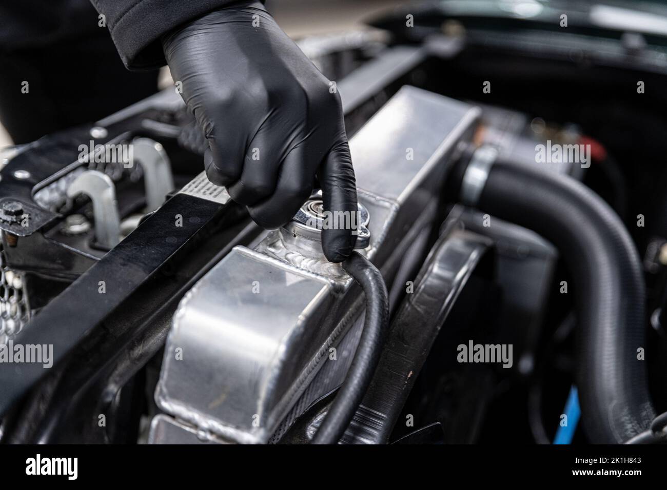 Il meccanico apre il tappo del bocchettone di rifornimento del liquido di raffreddamento nel radiatore di un'auto classica. Foto Stock