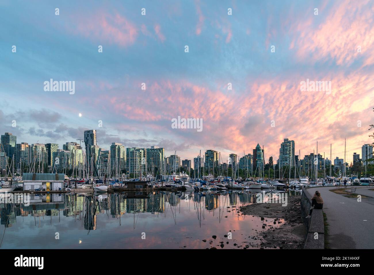 Donna che guarda uno splendido tramonto su Vancouver, Canada, con una vista riflessa del porto da Stanley Park. Foto Stock