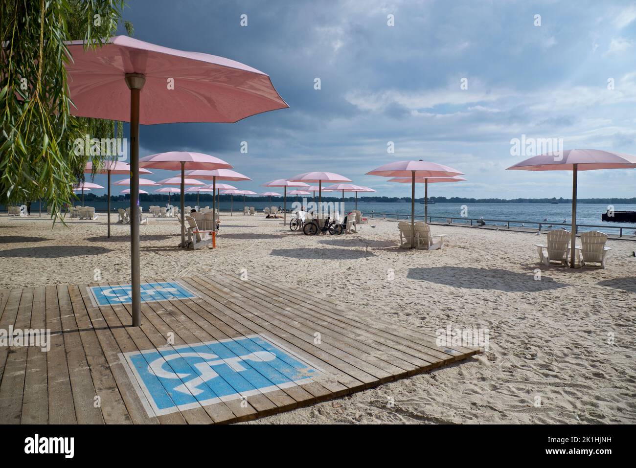 Zona di destinazione per disabili sulla spiaggia con ombrellone rosa Foto Stock
