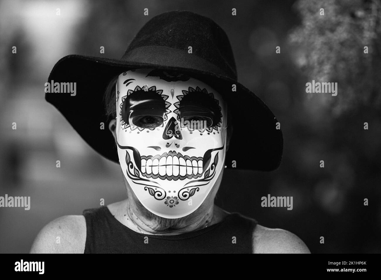 Ritratto in bianco e nero di una donna anziana con maschera e cappello catrina, che celebra Halloween e All Souls' Day, per strada. Celebrazione, costume Foto Stock