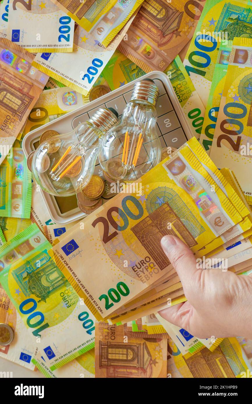 Aumento dei prezzi dell'elettricità in Europa.lampadina elettrica in mano sulle fatture in euro background.Paying bolles.Energy production crisi in Europa Foto Stock