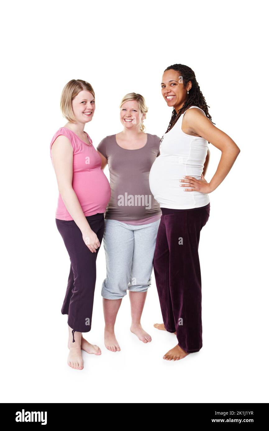 Ho il sostegno dei miei amici. Tre donne incinte sorridenti alla fotocamera mentre si levano in piedi su uno sfondo bianco. Foto Stock