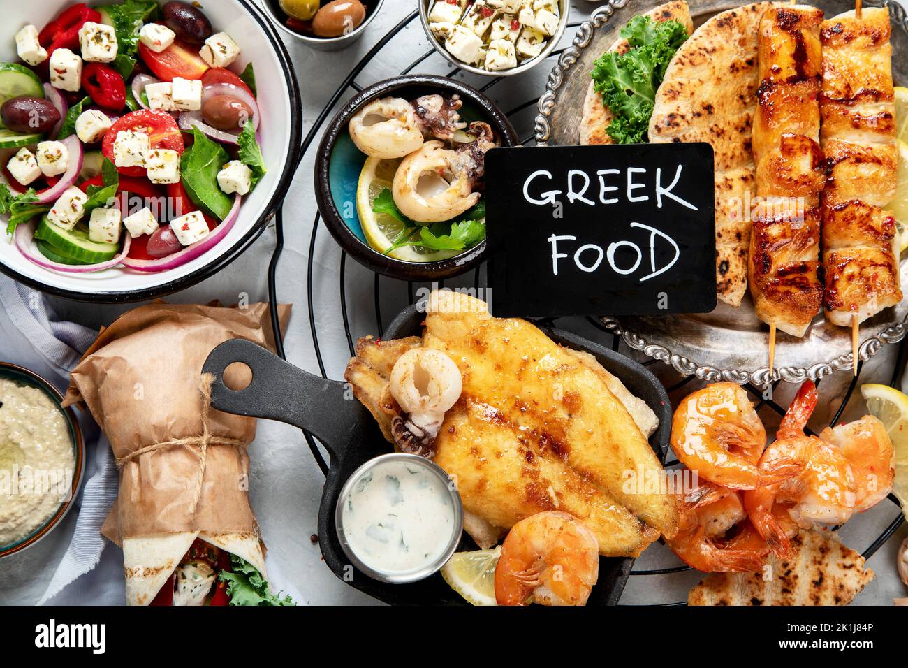 Cibo greco sfondo. Meze, gyros, souvlaki, pesce, pita, insalata greca, tzatziki, assortimento di feta, olive e polpette. Tradizionale greco diverso Foto Stock