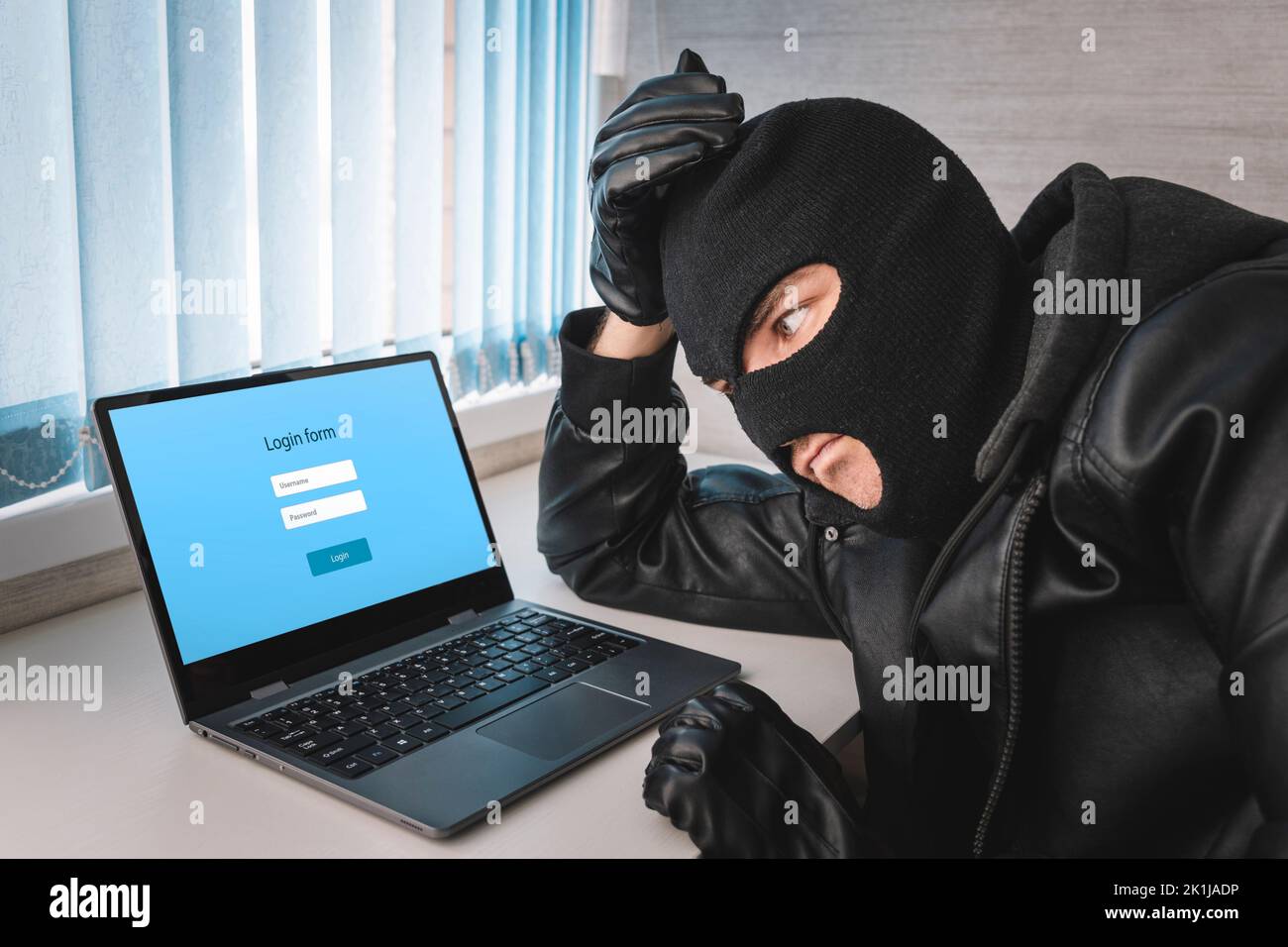 Hacker con schermata di accesso, concetto di frode informatica sfondo. Un ladro in una maschera balaclava sta pensando a una password per accedere. Il concetto di idente Foto Stock