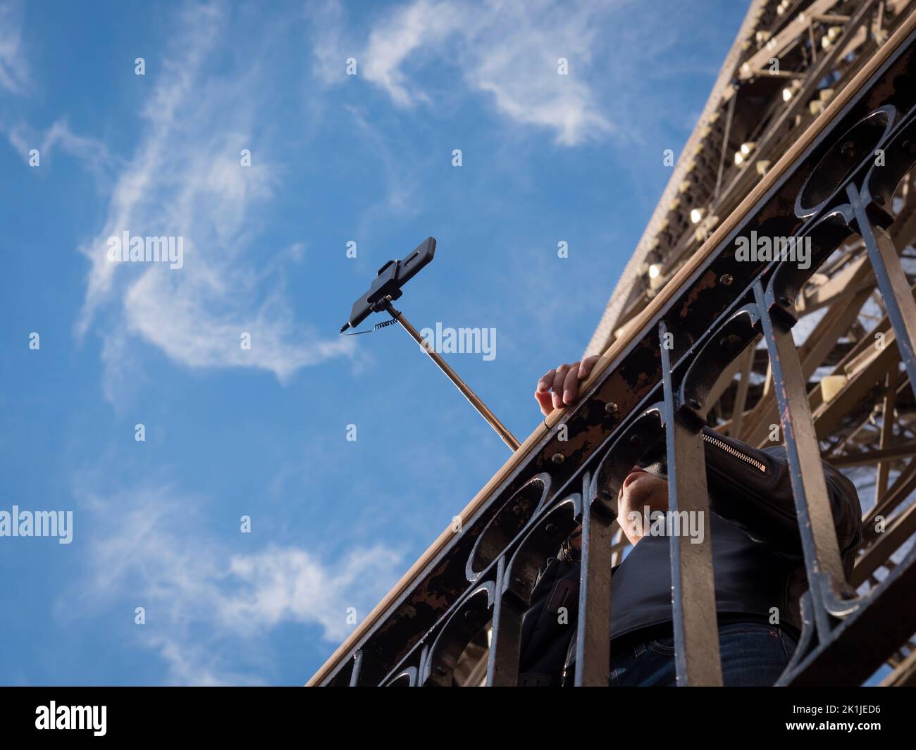 Parigi, Francia - 18 aprile 2022: Un turista in cima alla Torre Eiffel sta scattando una foto da smartphone utilizzando un selfie stick. Foto Stock